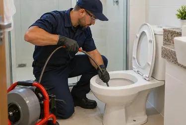 Profissional desentupindo um vaso sanitário em residência.