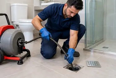 Técnico desentupindo um ralo em um banheiro.